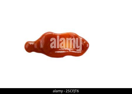 A small dollop of ketchup sits on a white surface, showcasing its glossy texture and rich red color. Stock Photo