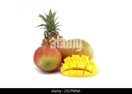 A group of fresh tropical fruits including pineapple and mango, with cubed mango on white background, exhibiting a vibrant and delicious presentation Stock Photo