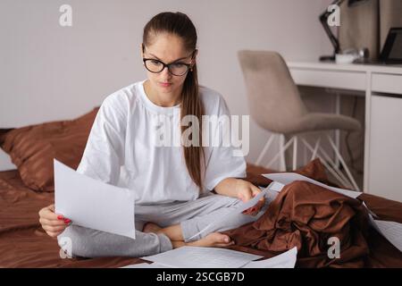 Woman with glasses works on financial documents at home Stock Photo