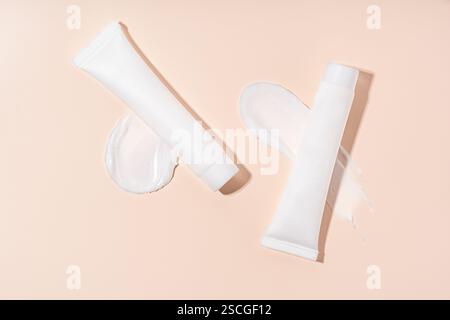 Mockup white tubes of cream for face lying on texture of smear, product line Stock Photo