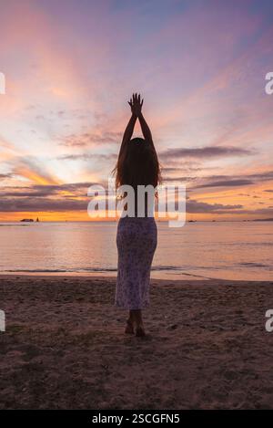 Silhouetted Woman on a Sandy Beach at Sunset in Hawaii Stock Photo