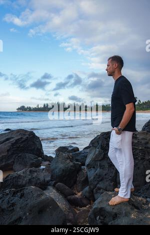 Man standing barefoot on rocks beside a flowing river in a natural ...