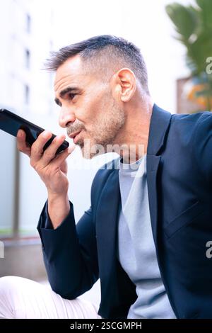 Businessman Using Voice Command on Smartphone Outdoors.Vertical Stock Photo