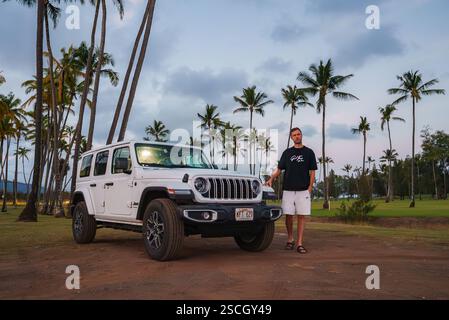 Man Standing by White Jeep Wrangler on Palm Lined Dirt Path in Hawaii Stock Photo