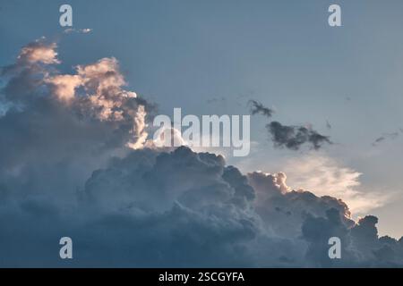 Stunning sky filled with towering cumulus clouds, illuminated by soft glow of sun. Contrast between light and shadow creates dramatic and atmospheric Stock Photo
