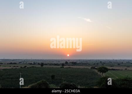 sunset view over hazy city with orange sky and electric pole at dusk Stock Photo
