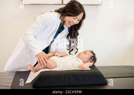 Doctor evaluating baby laying down on back Stock Photo