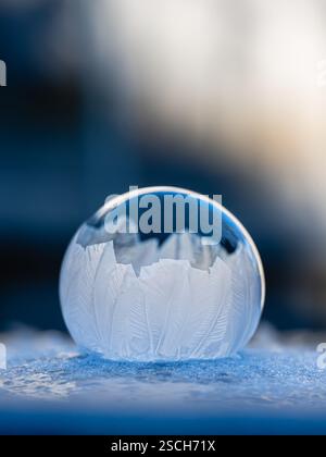 Close up of frozen soap bubble on snowy base in winter. Stock Photo