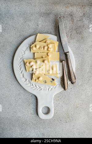 From above view of a white chocolate bar cut into pieces, placed on an ornate vintage cutting board with an old knife, showcasing a rustic, textured c Stock Photo