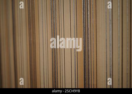 This image features a close-up of a textured wall adorned with vertical lines in various shades of beige and gray. The lines create a modern and elega Stock Photo