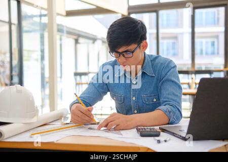 Architect working on blueprints at a modern workspace Stock Photo