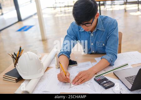 Architect working on blueprints at a modern workspace Stock Photo