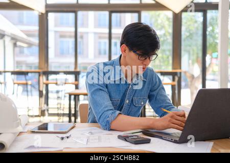 Architect working on blueprints at a modern workspace Stock Photo