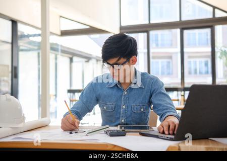 Architect working on blueprints at a modern workspace Stock Photo