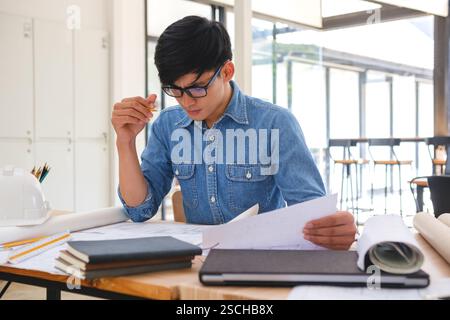 Architect working on blueprints at a modern workspace Stock Photo