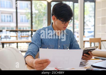 Architect working on blueprints at a modern workspace Stock Photo