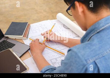 Architect working on blueprints at a modern workspace Stock Photo