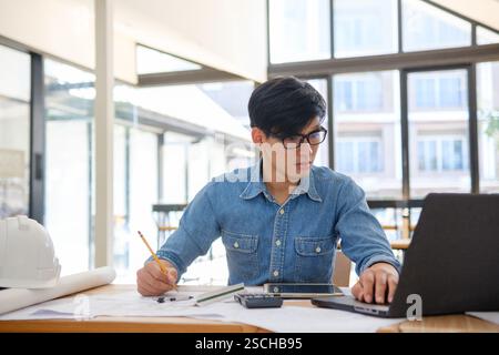 Architect working on blueprints at a modern workspace Stock Photo