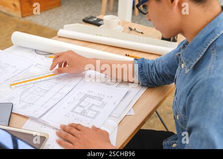 Architect working on blueprints at a modern workspace Stock Photo