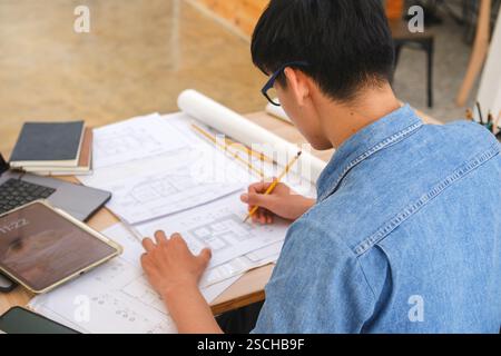 Architect working on blueprints at a modern workspace Stock Photo