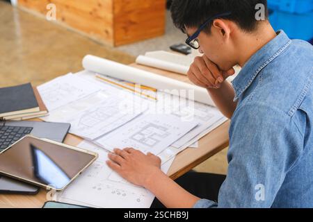 Architect working on blueprints at a modern workspace Stock Photo