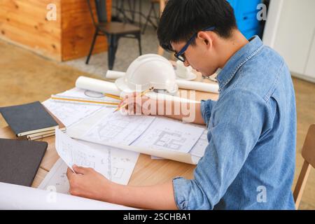 Architect working on blueprints at a modern workspace Stock Photo
