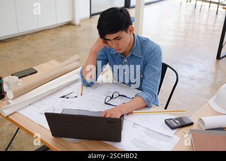 Architect and engineer working on a laptop with blueprints Stock Photo