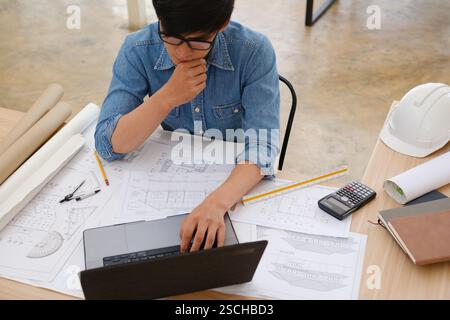 Architect and engineer working on a laptop with blueprints Stock Photo