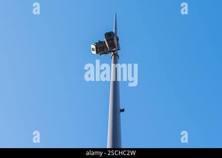 Low-angle view of surveillance cameras mounted on a tall pole, set against a clear blue sky. The image showcases security and technology in outdoor se Stock Photo
