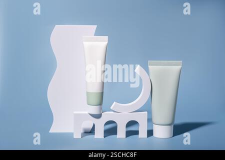 Two sleek cosmetic tubes placed stylishly on minimal white podiums against a soft blue background, embodying modern elegance and simplicity in product Stock Photo