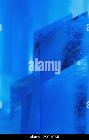 Close-up of intricately shaped ice structures illuminated with a cool blue glow at a temporary ice hotel in Swedish Lapland, capturing the serene beau Stock Photo