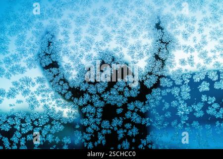 A captivating silhouette behind a frosty glass in Swedish Lapland, showcasing intricate ice crystal patterns on glass surface. Stock Photo