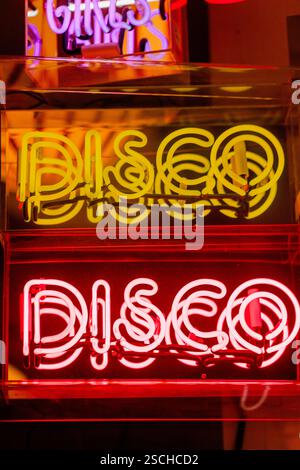 A vibrant neon sign featuring the word DISCO in bright yellow and red lights. Captured in the energetic nightlife of Stockholm. Perfect for party-them Stock Photo