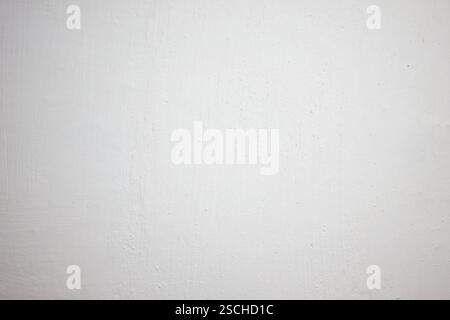 A clean, blank white wall is illuminated by soft natural light, creating an airy feel in a neutral interior setting. Ideal for backdrop or minimalisti Stock Photo