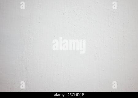 Soft light reveals the subtle textures of a white wall. The surface showcases small imperfections and variations, creating a neutral background ideal Stock Photo