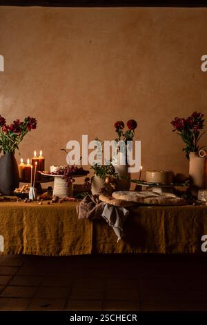 An elegantly styled dinner table adorned with candles, fresh flowers, and a variety of appetizers, set against a warm, textured backdrop. Stock Photo