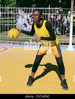 Sporty black woman in yellow sportswear sitting listening to music ...