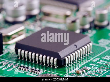 A detailed macro shot of a microchip securely mounted on a green printed circuit board, demonstrating intricate electronic design. Stock Photo