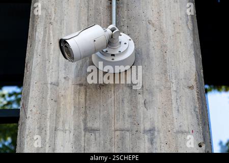 Security surveillance camera attached to a concrete pole, monitoring urban area, enhancing safety and surveillance capabilities. Stock Photo