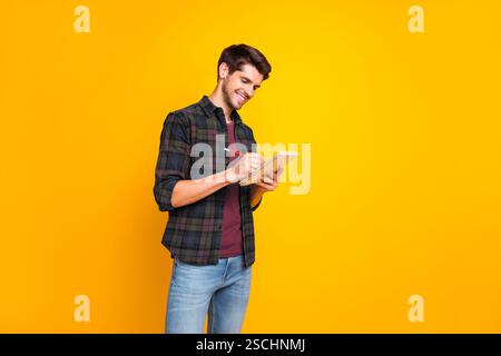 Profile photo of nice guy with organizer in hands making notes creating startup idea wear casual checkered shirt and jeans isolated yellow color Stock Photo