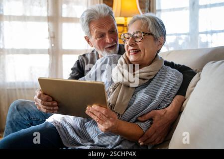 Elderly couple enjoying a tablet. Senior man and woman smiling, bonding over technology. Stock Photo