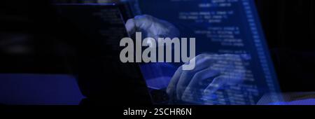 Modern workspace with blue virtual interface displaying fictional programming text. Hands typing on laptop, illustrating cybersecurity Stock Photo