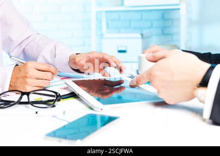 Professionals collaborating on a digital project using a tablet in a modern office setting during work hours Stock Photo