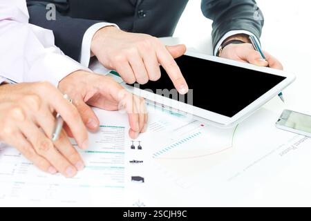 Business team collaborates on tablet while reviewing documents in a modern office environment Stock Photo