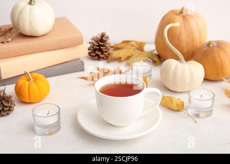 Cup of tea, burning candles and pumpkins on white background Stock Photo
