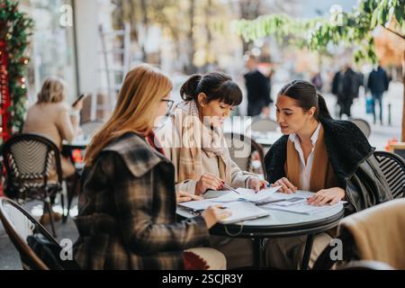 Three businesswomen collaborating while seated outdoors at a cozy café Stock Photo