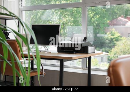 Modern workplace with computer and printer near window in office Stock Photo