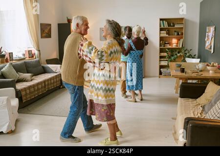 Senior biracial couples dancing slowly in living room of nursing home Stock Photo