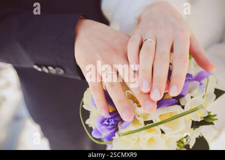 Couple exchanging wedding vows holding bouquet with rings in elegant setting Stock Photo