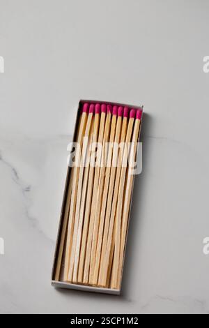 A box of matches with a pink and red head. The box is open and the matches are lined up Stock Photo